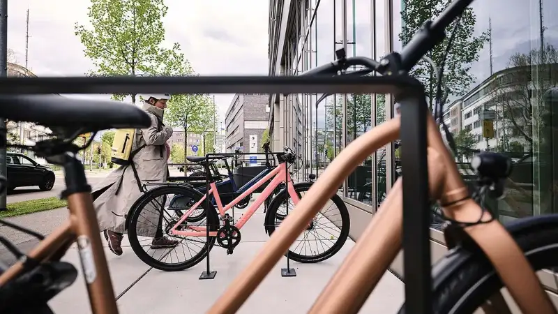 Eine Frau kommt mit ihrem Fahrrad am Büro an Eine Frau kommt mit ihrem Fahrrad am Büro an